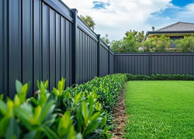 Charcoal steel sheet fence along a lawn and garden bed