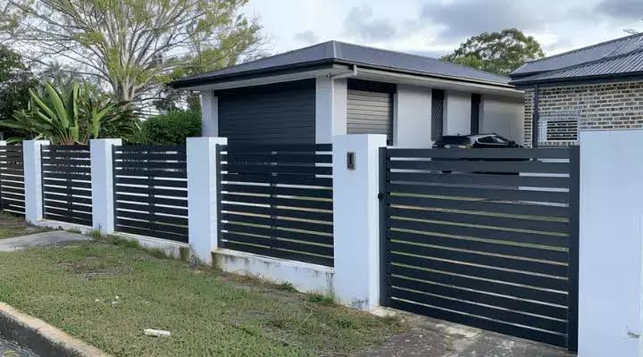 Charcoal slat fence panels between white rendered pillars